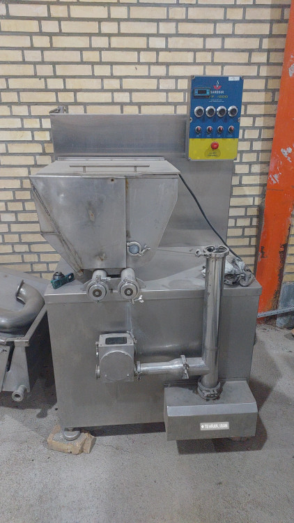 Close-up of industrial fruit feeder machine adding strawberry pieces and chocolate chips into ice cream, luxury food factory, realistic industrial environment